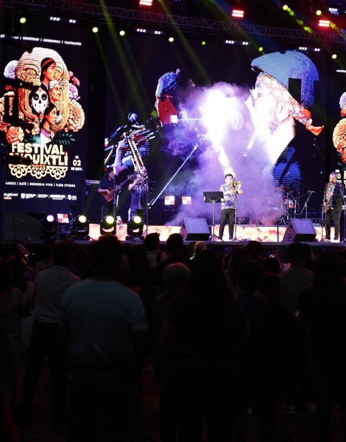 Escenario de festival con pantallas LED, humo e iluminación durante una presentación en vivo