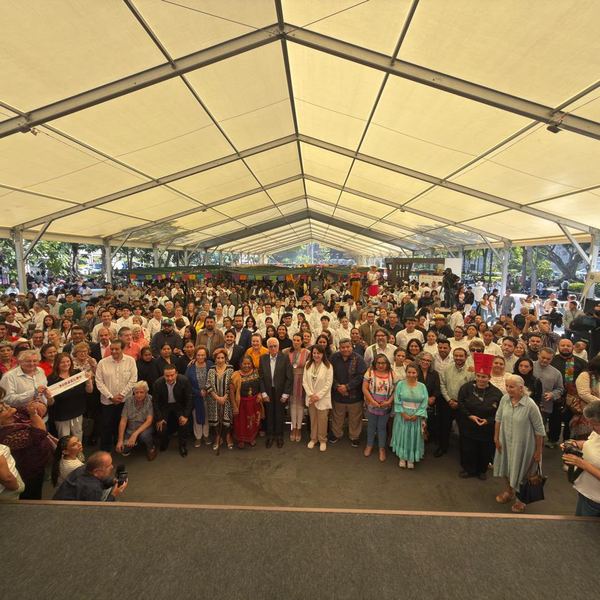 Foro con cientos de asistentes en mesas largas bajo una carpa