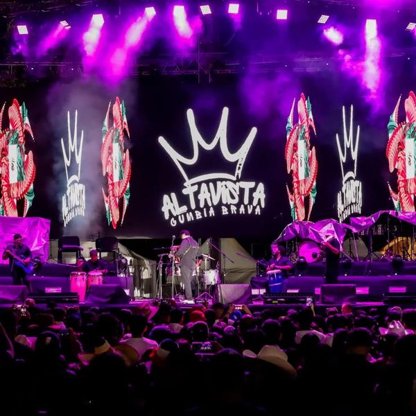 Escenario con iluminación morada y pantallas LED durante un concierto de cumbia