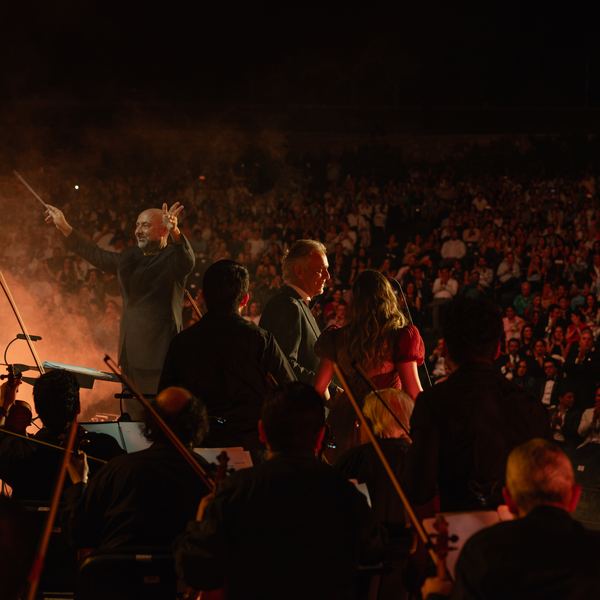 Orquesta y público vistos desde el escenario durante un concierto con humo e iluminación
