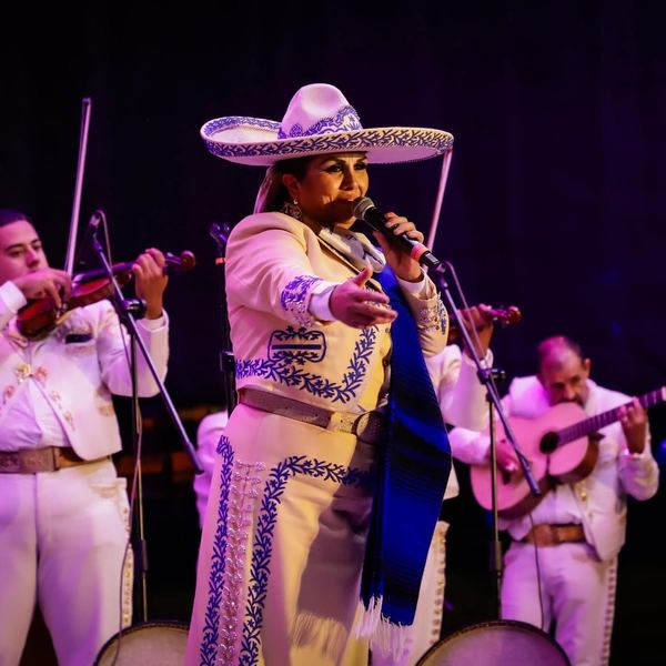 Cantante con traje de charro y mariachi en el escenario de un evento de gobierno