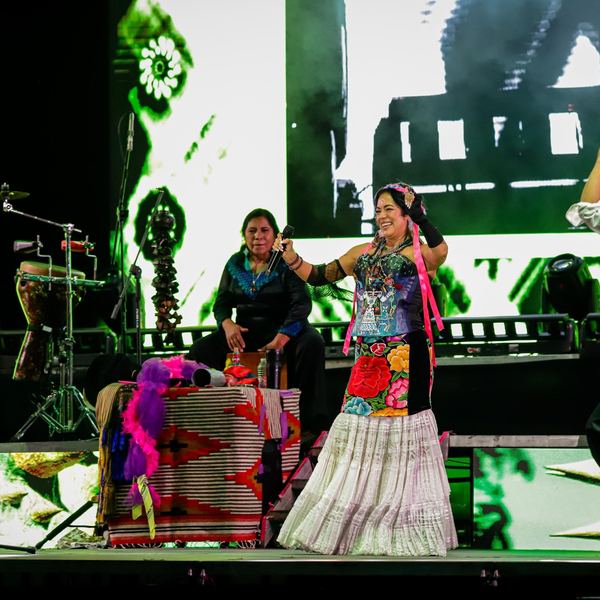 Bailarines y músicos en un escenario con pantallas LED de colores