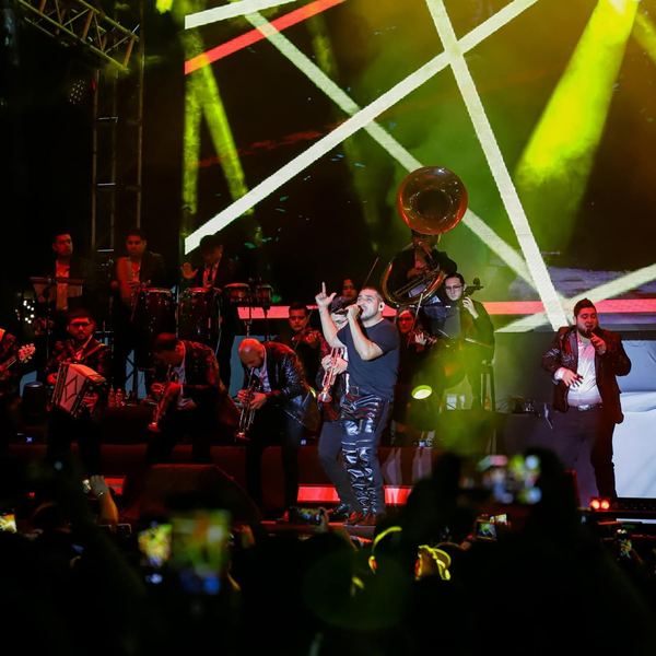 Banda en vivo con luces y rayos láser verdes y amarillos en un festival nocturno
