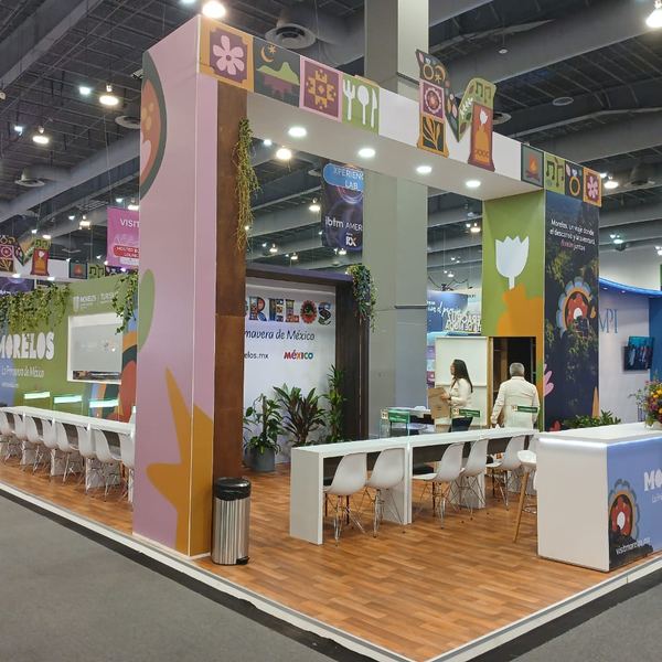 Stand de Morelos con jardín vertical y pantallas en una feria de turismo